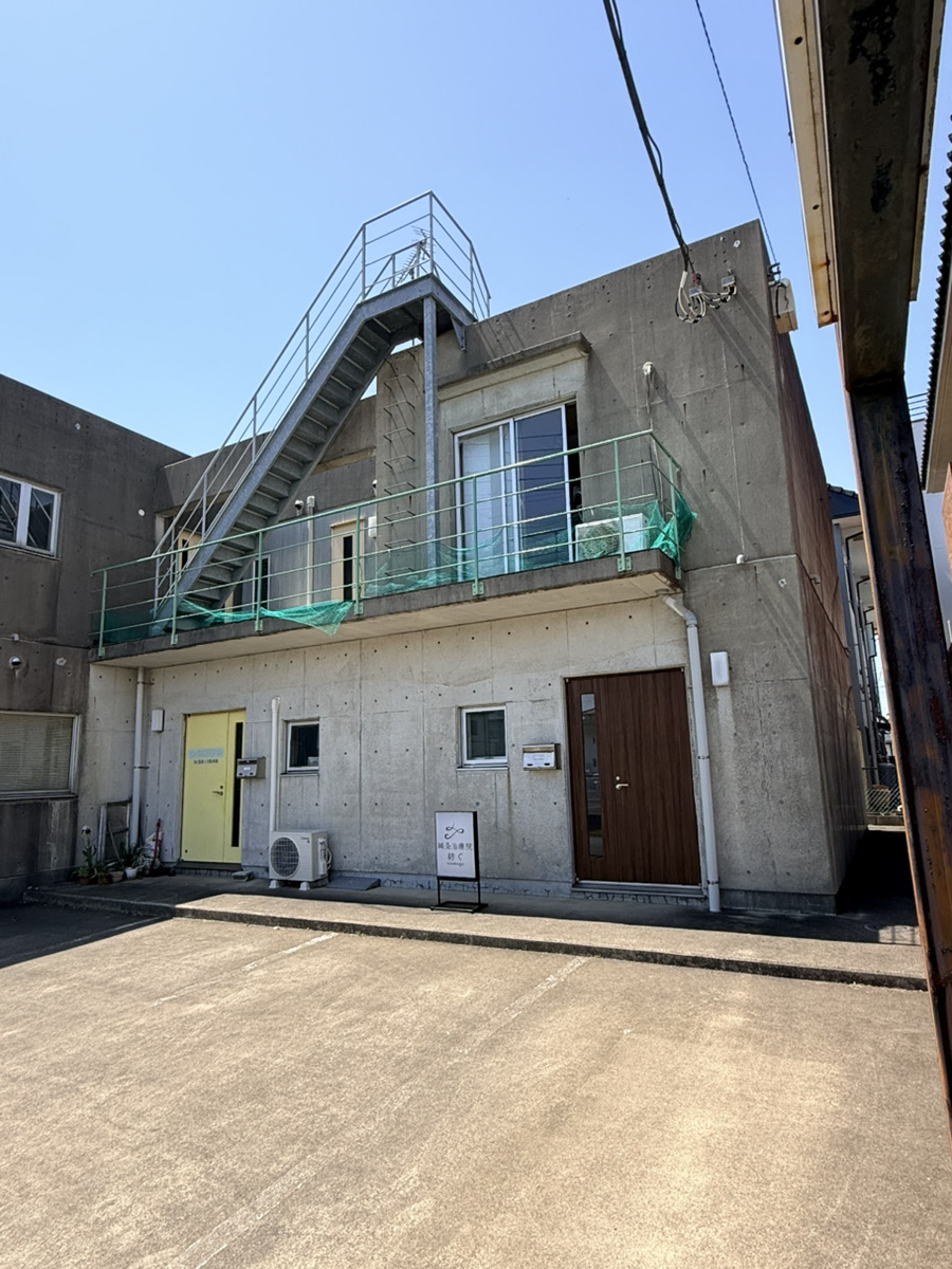 Modern concrete building with rooftop deck, stairs, and green railings in industrial area
